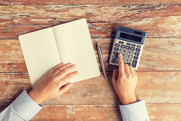 Primo piano delle mani con calcolatrice e notebook — Foto Stock