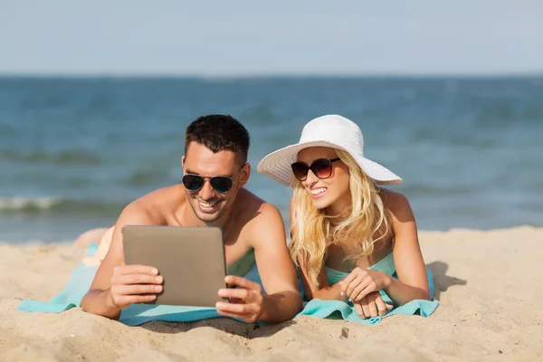 Ευτυχισμένο ζευγάρι με tablet pc κάνοντας ηλιοθεραπεία στην παραλία — Φωτογραφία Αρχείου