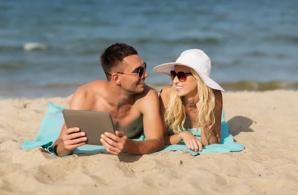 Feliz pareja con tableta pc tomar el sol en la playa — Foto de Stock