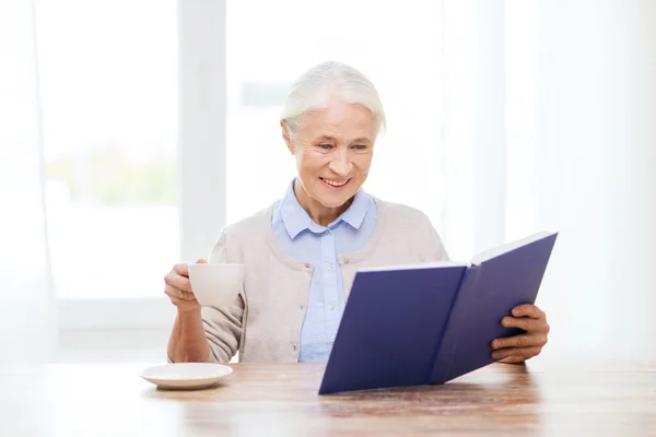 Щаслива усміхнена старша жінка читає книгу вдома — стокове фото