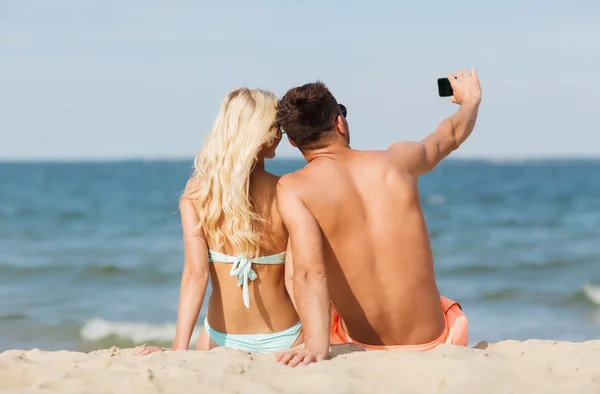 Ευτυχισμένο ζευγάρι στο μαγιό που κάθεται στην παραλία το καλοκαίρι — Φωτογραφία Αρχείου