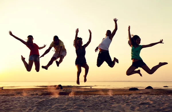 Teman-teman tersenyum menari dan melompat di pantai Stok Foto Bebas Royalti
