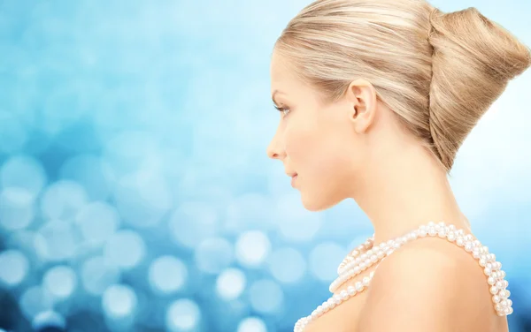 Schöne Frau mit Perlenkette über blauem Grund — Stockfoto