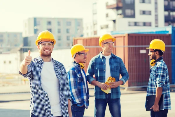 Gruppe av smilende byggmestere i harde hatter utendørs – stockfoto