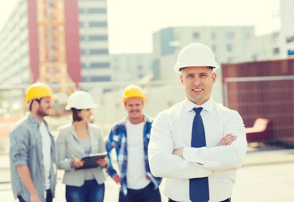 Grupo de construtores sorridentes em hardhats ao ar livre — Fotografia de Stock