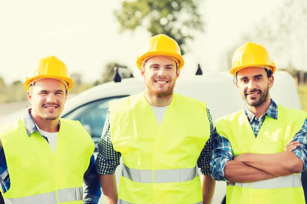 Grupa budowniczych uśmiechający się w hardhats na zewnątrz — Zdjęcie stockowe