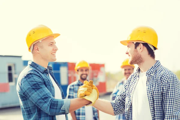 Grupp av leende byggare i hardhats utomhus — Stockfoto