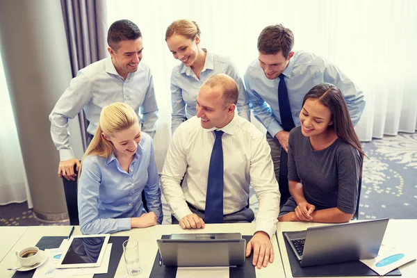 Pessoas de negócios sorridentes com laptop no escritório — Fotografia de Stock