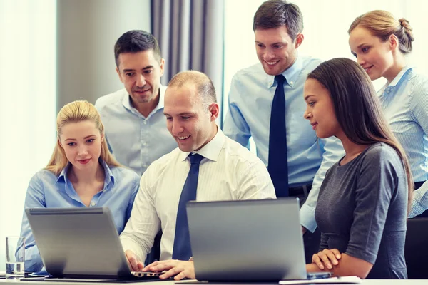 Empresários sorridentes com laptops no escritório — Fotografia de Stock