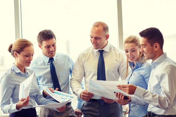 Gelukkig zakenmensen met papieren talkig in office — Stockfoto