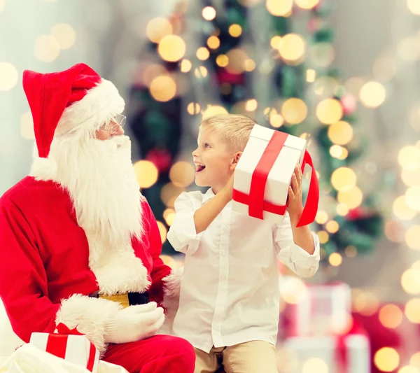 Lächelnder kleiner Junge mit Weihnachtsmann und Geschenken — Stockfoto