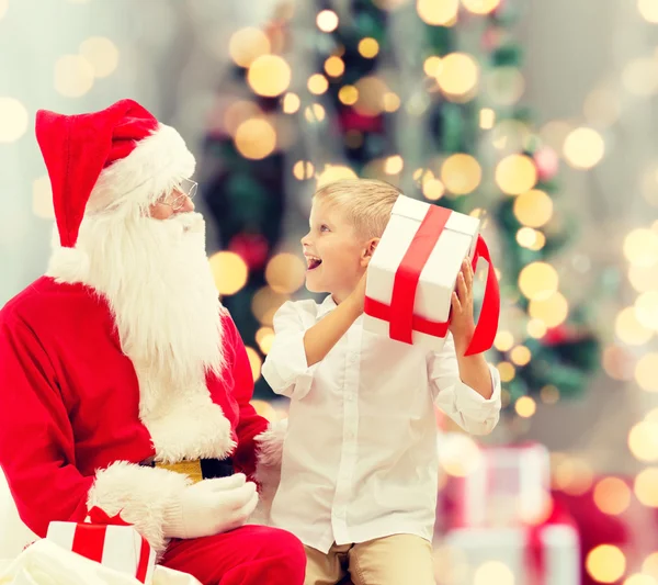 Petit garçon souriant avec santa claus et cadeaux — Photo