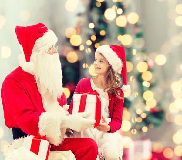 Улыбающаяся маленькая девочка с Санта Клаусом и подарками — стоковое фото