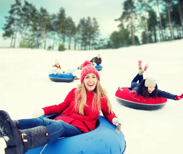 Group of happy friends sliding down on snow tubes — Stock Photo, Image