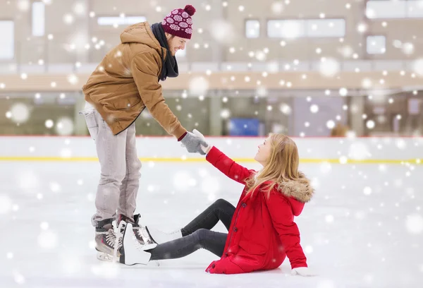Hombre ayudando a las mujeres a levantarse en pista de patinaje —  Fotos de Stock