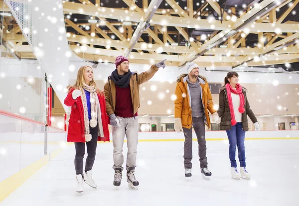 Heureux amis pointant doigt sur patinoire — Photo