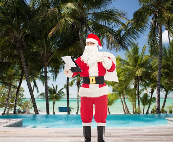 Человек в костюме Санта-Клауса с блокнотом и сумкой — стоковое фото