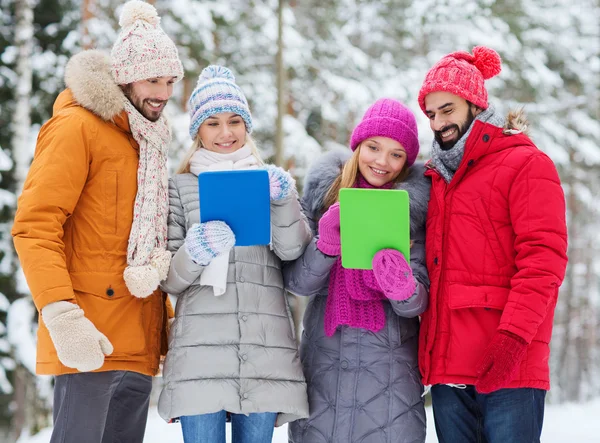 Lachende vrienden met tablet pc in winter forest — Stockfoto