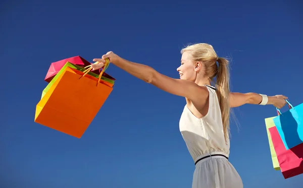 Mulher sorrindo com as mãos subindo saco de compras — Fotografia de Stock