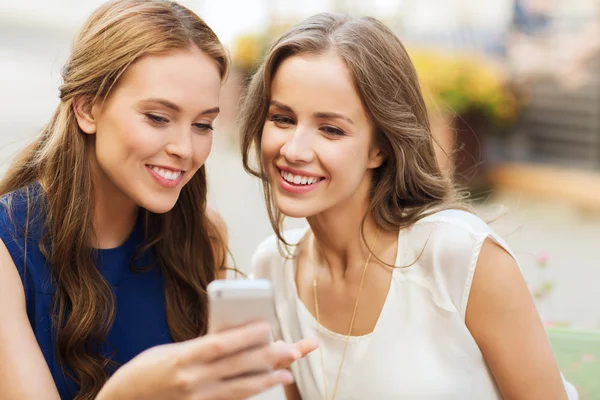 Mujeres jóvenes felices con teléfono inteligente en la cafetería al aire libre — Foto de Stock