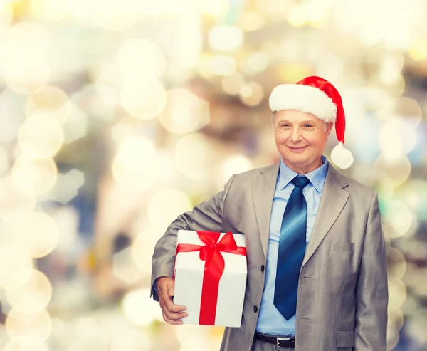 Lächelnder Mann im Anzug und Weihnachtsmannmütze mit Geschenk Stockbild