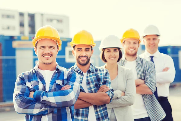 Groupe de constructeurs souriants en hardhats à l'extérieur Images De Stock Libres De Droits