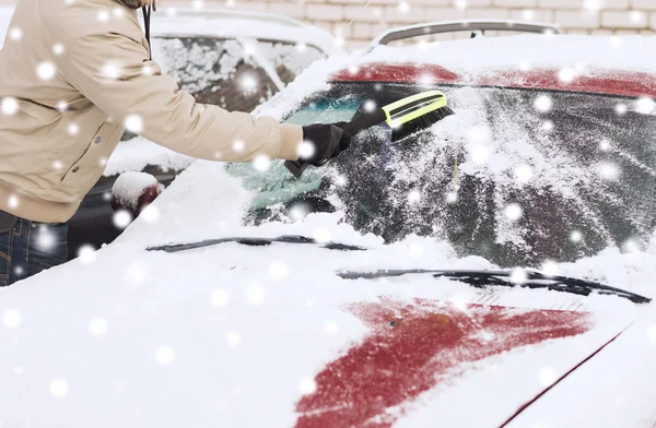 Gros plan de l'homme nettoyant la neige de la voiture Images De Stock Libres De Droits