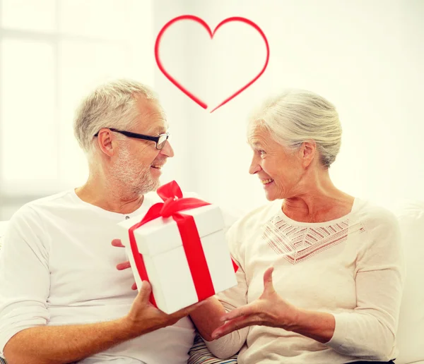 Gelukkig senior paar met geschenkdoos thuis — Stockfoto