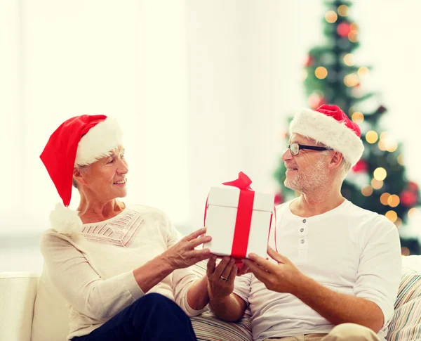Glad äldre par i santa hattar med presentask — Stockfoto