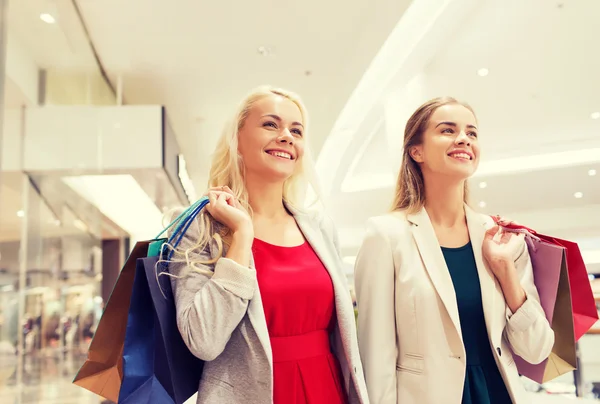 Glada unga kvinnor med shoppingkassar i gallerian — Stockfoto