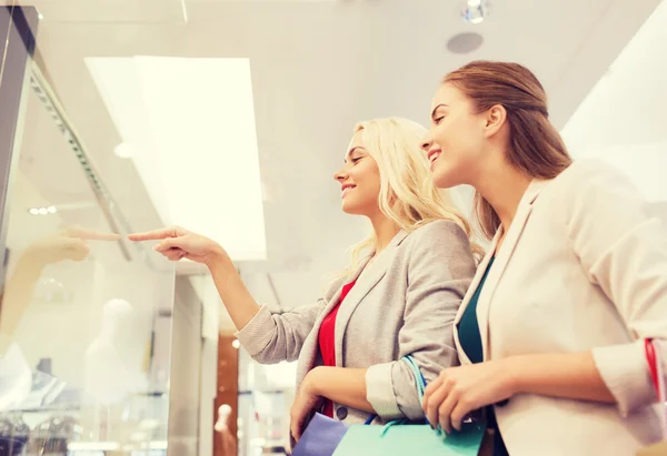 Gelukkig jonge vrouwen met boodschappentassen in winkelcentrum — Stockfoto