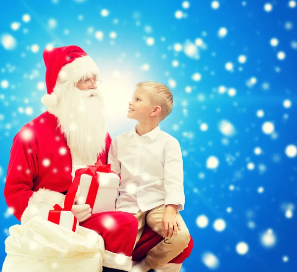 Улыбающийся маленький мальчик с Санта-Клаусом и подарками — стоковое фото