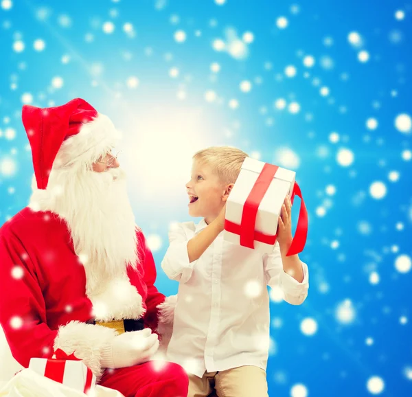 Petit garçon souriant avec santa claus et cadeaux — Photo