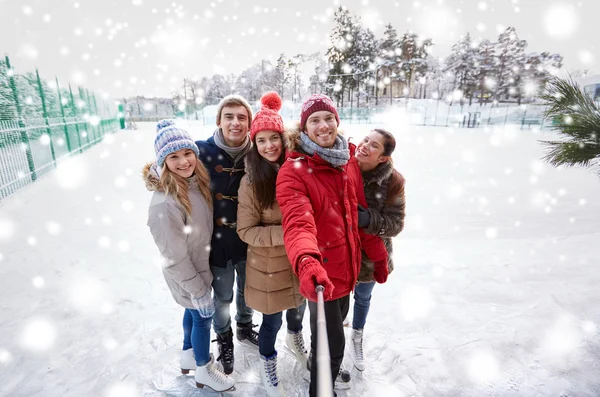 Happy friends with smartphone on ice skating rink — Stock Photo, Image