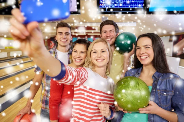 Happy friends with smartphone in bowling club — Stock Photo, Image