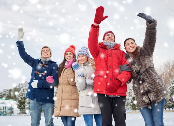 Happy friends waving hands on ice rink outdoors — Stock Photo, Image