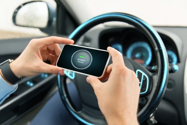 Handen met start motor icoon op smartphone in auto — Stockfoto