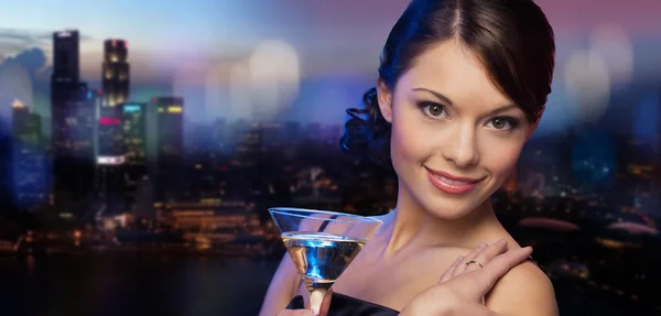 Smiling woman holding cocktail over night city — Stock Photo, Image