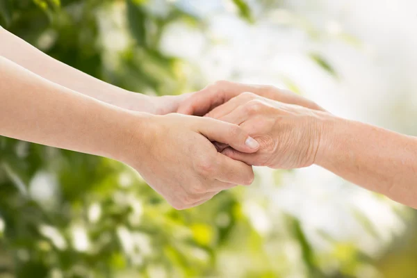 Primer plano de la mujer mayor y joven tomados de la mano — Foto de Stock