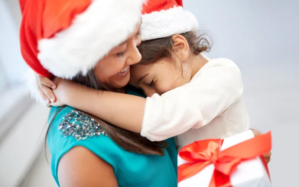 Felice madre e bambina in cappelli di Babbo Natale a casa — Foto Stock