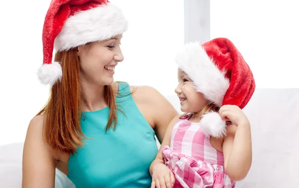 Gelukkig moeder en meisje in santa hoeden thuis — Stockfoto