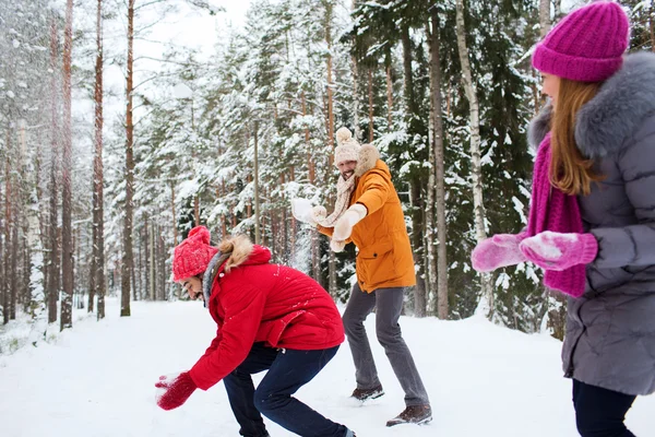 Glada vänner spelar snöboll i vinter skog — Stockfoto