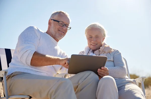 Feliz pareja de ancianos con tableta pc en la playa de verano —  Fotos de Stock