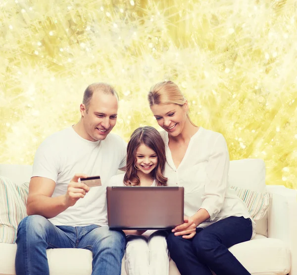 Familia feliz con ordenador portátil y tarjeta de crédito — Foto de Stock