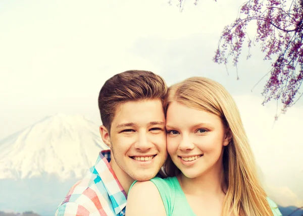 Sonriente pareja abrazándose sobre montañas fondo —  Fotos de Stock