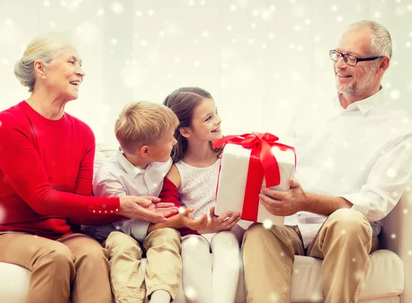 Улыбающиеся бабушки и дедушки и внуки с подарком — стоковое фото