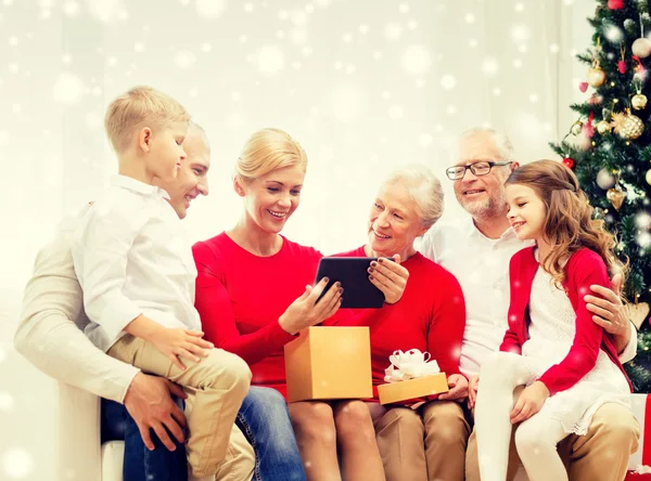 Família sorrindo com tablet pc e caixa de presente em casa — Fotografia de Stock