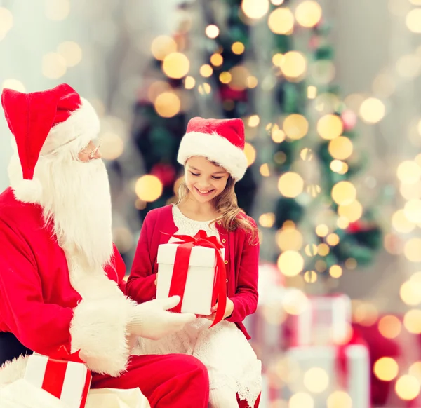 Niña sonriente con santa claus y regalos — Foto de Stock