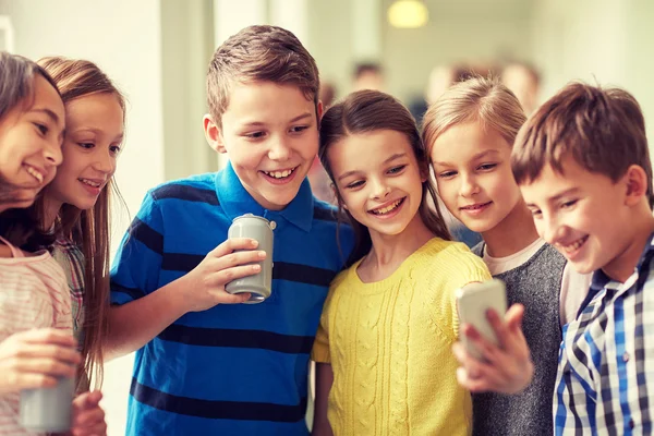 Skupina dětí školy s smartphone a soda plechovky — Stock fotografie