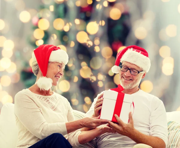 Feliz pareja de ancianos en sombreros de santa con caja de regalo — Foto de Stock